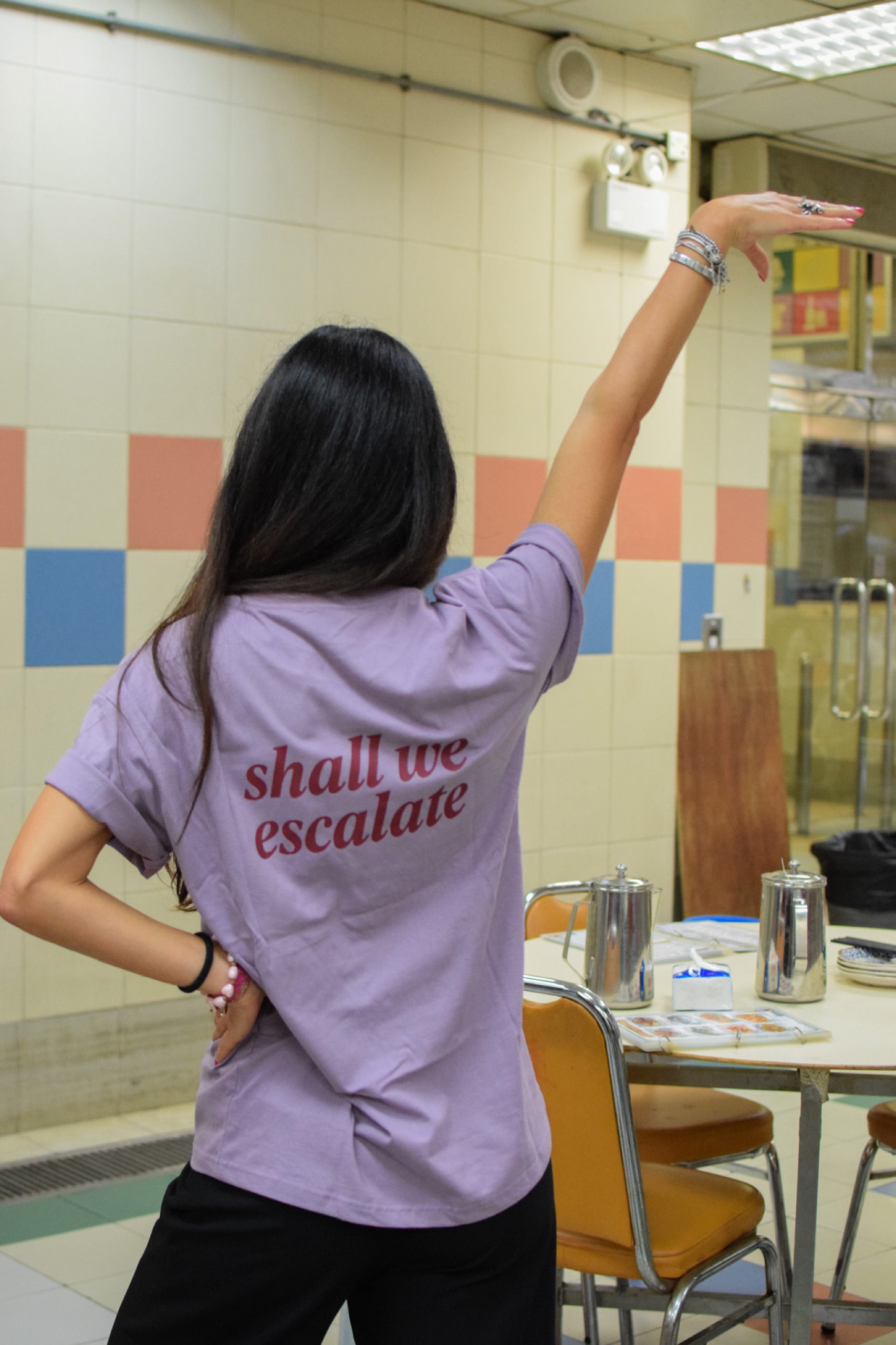Person wearing the lavender shall we escalate SORRY BABY shirt at the launch