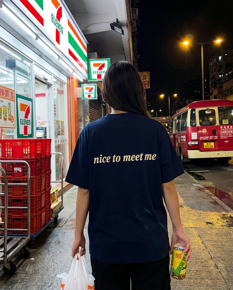Navy SORRY BABY shirt reading nice to meet me outside a Hong Kong 7-Eleven at night